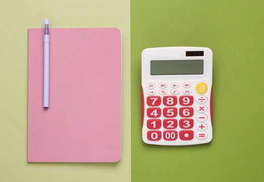 Notepad with a calculator on a green background. Top view