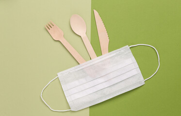 Eco cutlery with medical mask on green background