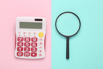 Calculator with a magnifying glass on a blue-pink pastel background. Business concept. Top view