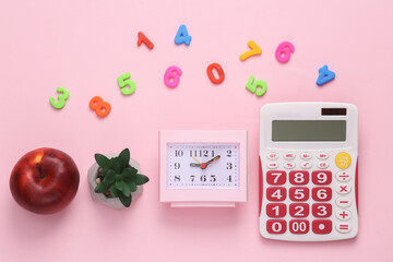 School or business accessories on a pink background. Calculator, clock, decorative plant and apple on a pink background with numbers. Top view. flat lay