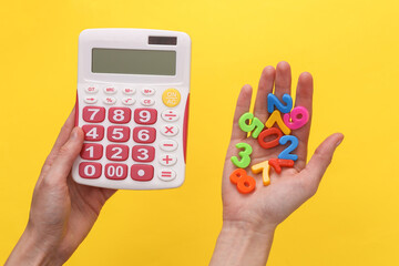 Business, education concept. Hands holding a calculator and colored letters on a yellow background