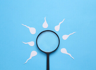 Diagnosis of male reproductive function. Spermatozoa, male seed with a magnifying glass on a blue...