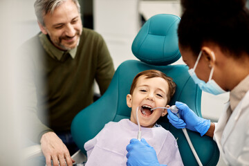 Happy boy having his teeth checked by female dentist.
