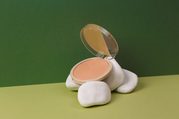 Aesthetic beauty or makeup still life. Powder box with stone on two tone green background. Natural cosmetics