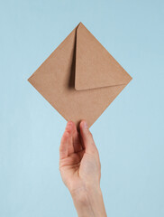Craft envelope in female hand on a blue background.
