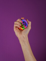 Woman's hand squeezing antistretch sensory Snappers toy on a purple background