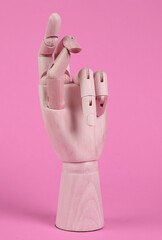 Wooden hand snaps fingers on pink background