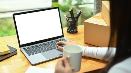 Fototapeta premium Young woman checking product purchase order on laptop computer. E-Commerce, online business, online sales concept