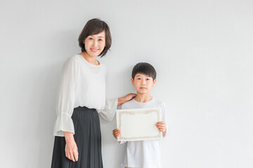 賞状を持つ男の子と女性（コンクール・合格・習い事）
