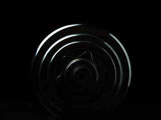 Stainless steel dumbbell on dark background.