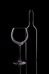 Wine glass and bottle of wine on dark background.