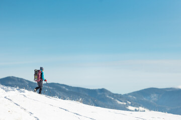 young girl with a backpack on a winter hike walks through the snow.