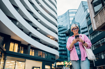 Young plus size woman using smartphone while walking in the city.