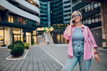 Young plus size woman using smartphone while walking in the city.