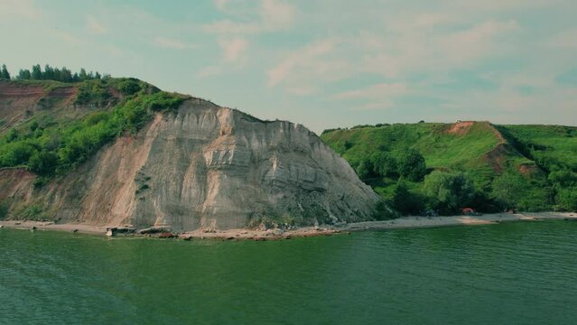 Shot on a drone. High hilly bank on the river bank. A place of rest for tourists with tents. Wild camping on the beach.