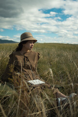 young lady with sketch book on the meadow looking side