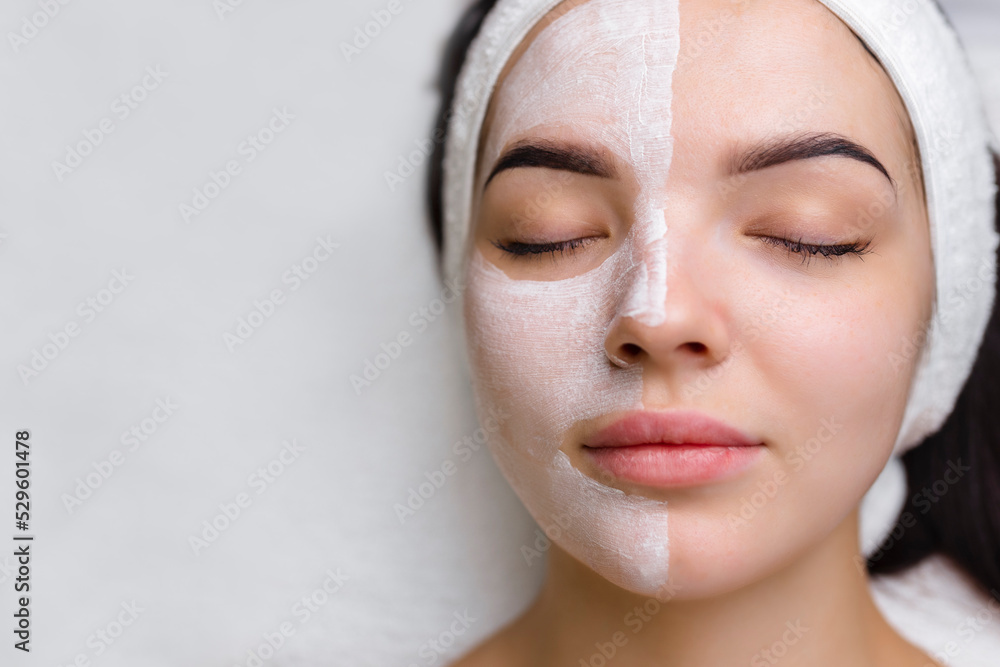 Wall mural Close-up shot of a woman getting facial treatment with clay mask. Cosmetology and spa