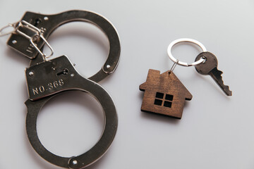 House with key and handcuffs close-up. Fraud in real estate concept