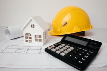 Architecture and engineering concept. Yellow helmet, money and model of house on drawings