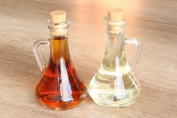 Obraz na płótnie Canvas Decanters with vegetable oil (olive, sunflower or linseed) on a wooden table. Decanters with white wine and cognac on a wooden tabletop.