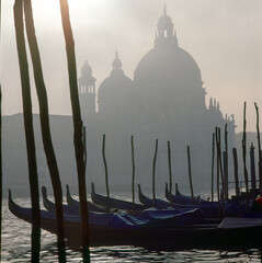 Venezia. La Salute in controluce con gondole sul Canal Grande, nel caligo. © Guido