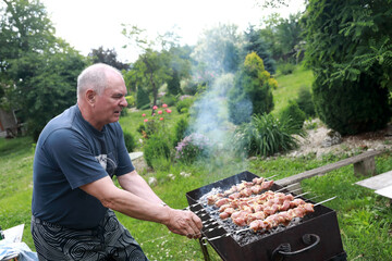 Man cooking pork barbecue on skewers