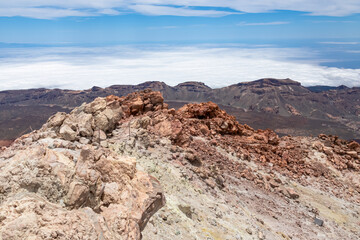 Scenic view from summit of volcano Pico del Teide over the island of Tenerife, Canary Islands, Spain, Europe. Vista on barren landscape, solidified lava, ash, pumice. Valley and sea covered in clouds