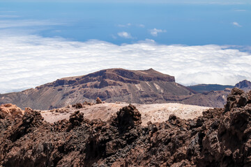 Scenic view from summit of volcano Pico del Teide over the island of Tenerife, Canary Islands, Spain, Europe. Vista on barren landscape, solidified lava, ash, pumice. Valley and sea covered in clouds
