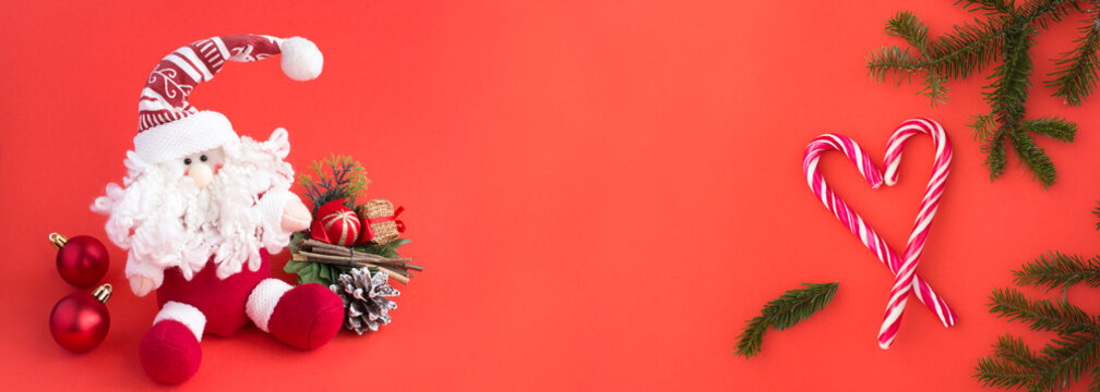 Christmas banner. Christmas toy Santa Claus and candy cane on the red background. Copy space.