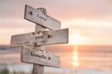 love you isabella written on wooden signpost outdoors on the beach with romatic sunset in the back. Power words and popular name concept.