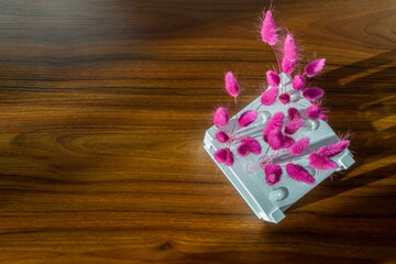 Bouquet of purple lagurus in white pedestal with test tubes on the wooden table. Copy space.