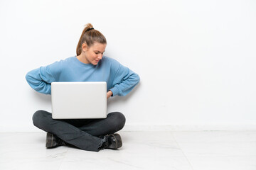 Young woman with a laptop sitting on the floor suffering from backache for having made an effort