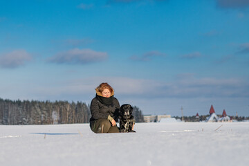 Fototapeta na wymiar A young beautiful girl walks a purebred Labrador on a snowy field. There is artistic noise.