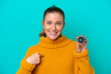 Young caucasian woman holding compass isolated on blue background with surprise facial expression © luismolinero