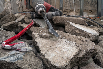 Selective focus. The crowbar and jackhammer lies on large pieces of broken cement walls and...