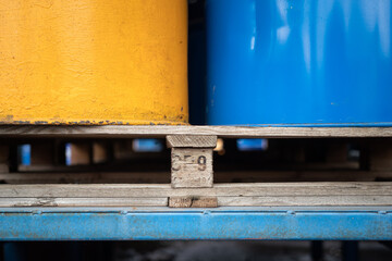 Close-up at wood pallet with metal chemical barrels at the factory storage. Industrial equipment object photo, selective focus.