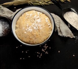 Raw dough pastry in a bowl on dark background.