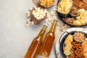 Assortment of beer and salty snacks on light background.