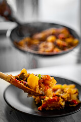 woman puts food from a frying pan into a plate