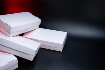 Healthy food sushi delivery packege in white eco boxes. Close-up containers on black background with red backlight.