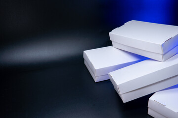 Healthy food sushi delivery packege in white eco boxes. Close-up containers on black background with blue backlight.