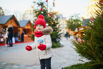 Happy cheerful preschooler girl on a Christmas market in Paris, France