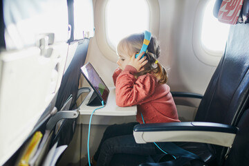 4 year old girl using tablet while travelling by plane