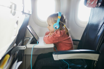 4 year old girl using tablet while travelling by plane