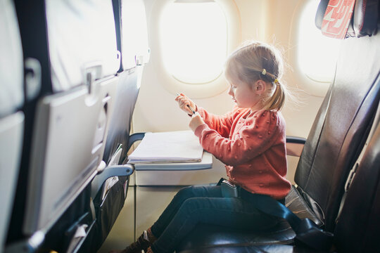 4 year old girl drawing while travelling by plane