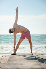 Young man doing yoga outdoor near sea, relax lifestyle