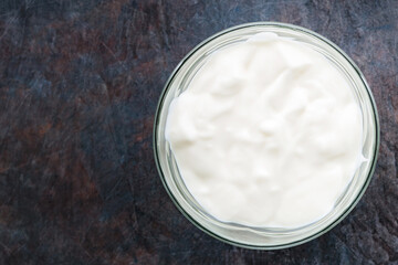 Yogurt in a bowl. Greek yogurt on a dark background. Dairy product for a healthy breakfast. Top view. Copy space