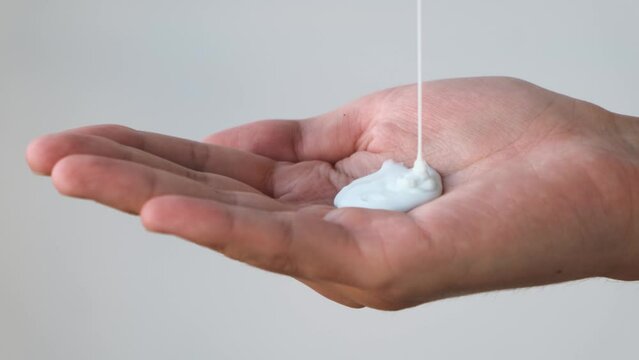 Man pouring a portion of shampoo into the palm, close-up