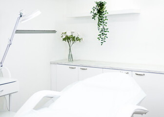 cosmetology cabinet interior with white cosmetology chair, white walls and flowers. business in cosmetology concept