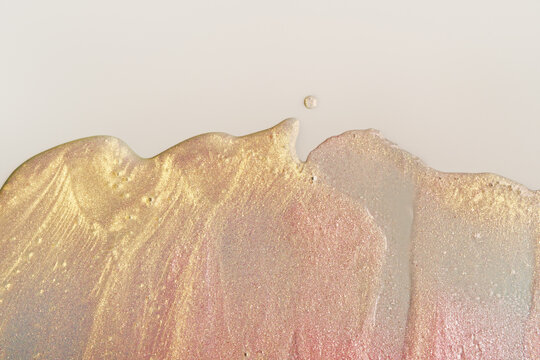 Beauty gel texture with pink and golden particles. Shining highlighter background with brush strokes